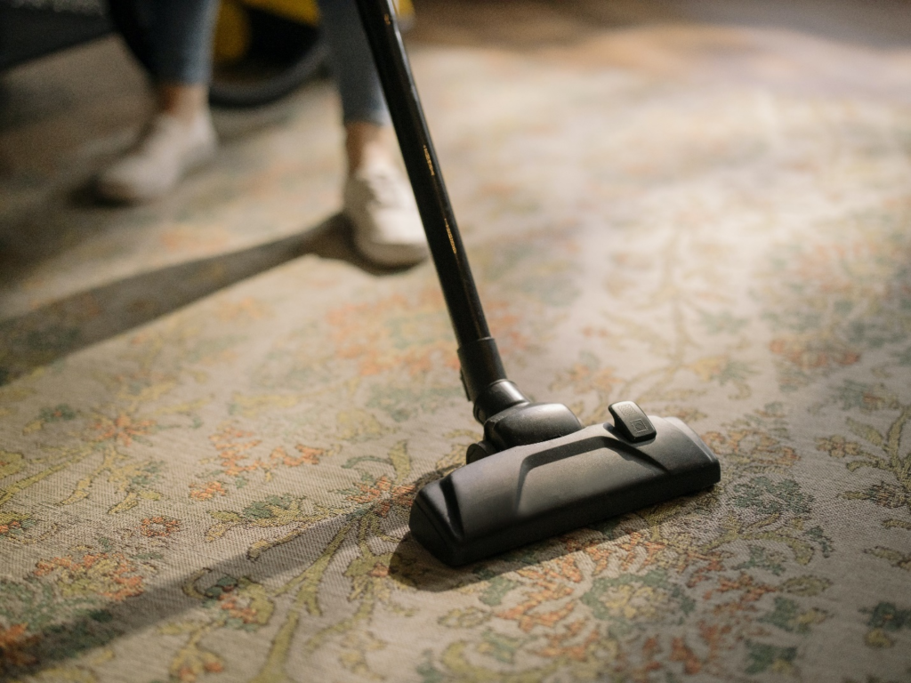 A Person Cleaning Carpet With Vacuum Cleaner